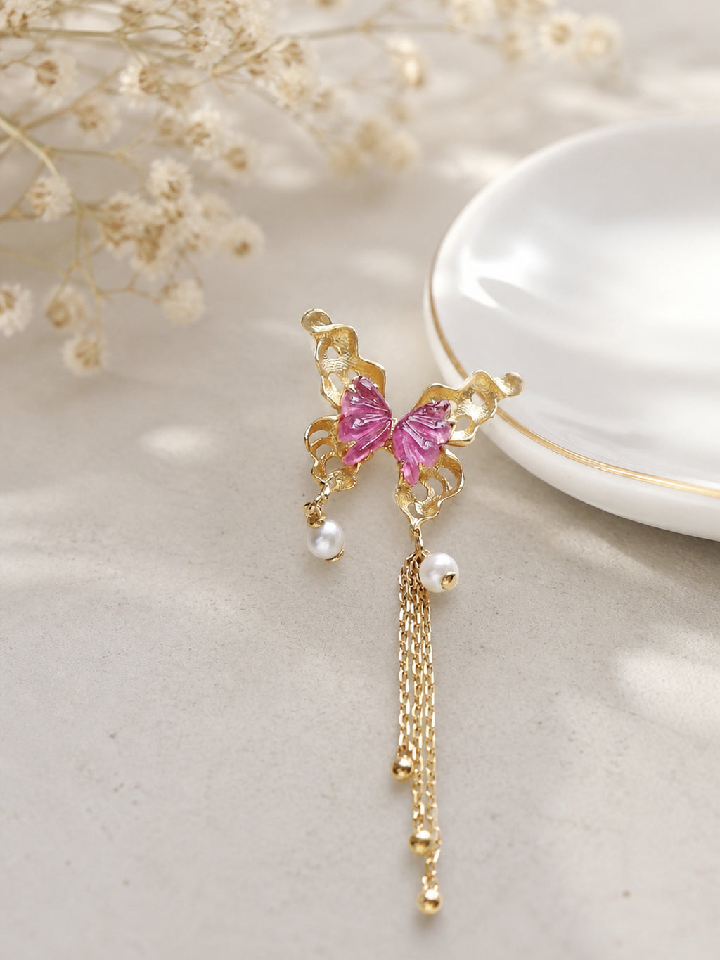 Gold butterfly pendant with pink stones, pearl drops, and long chain tassel