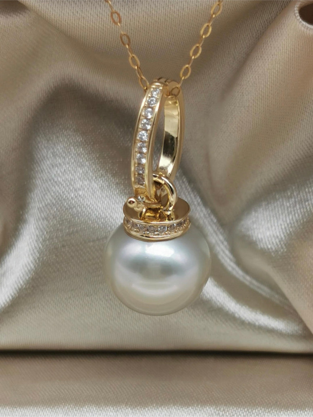 Gold pearl pendant with round pearl center and gemstone-set loop