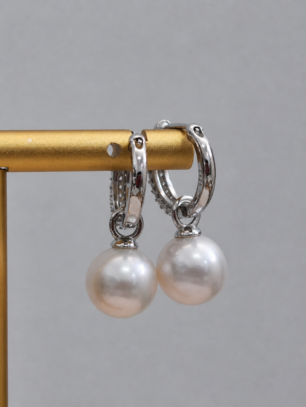 Silver hoop lock earrings with round pearl drops hanging from polished hoops