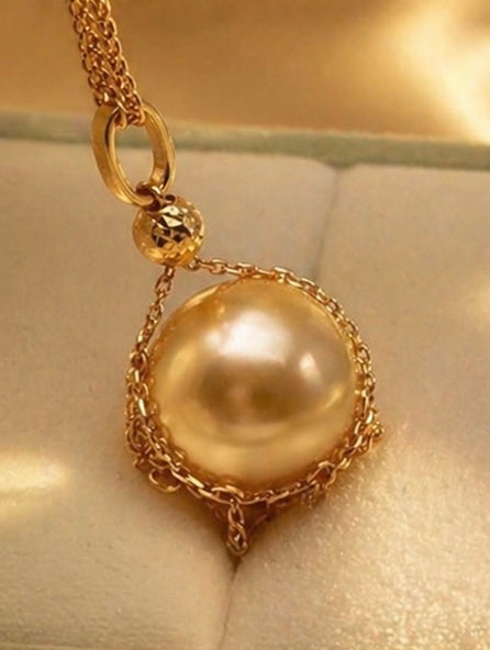 Close-up of 18k gold pearl pendant on chain with round pearl centerpiece