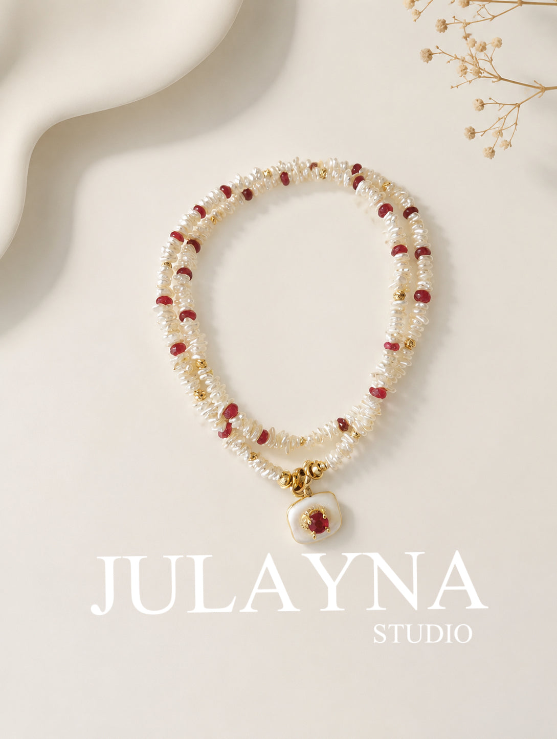 Keshi pearl necklace with red ruby beads and gold clasp, laid on a display card