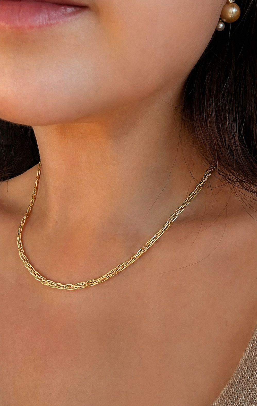 Three-tone braided gold necklace worn at the neckline with pearl pendant