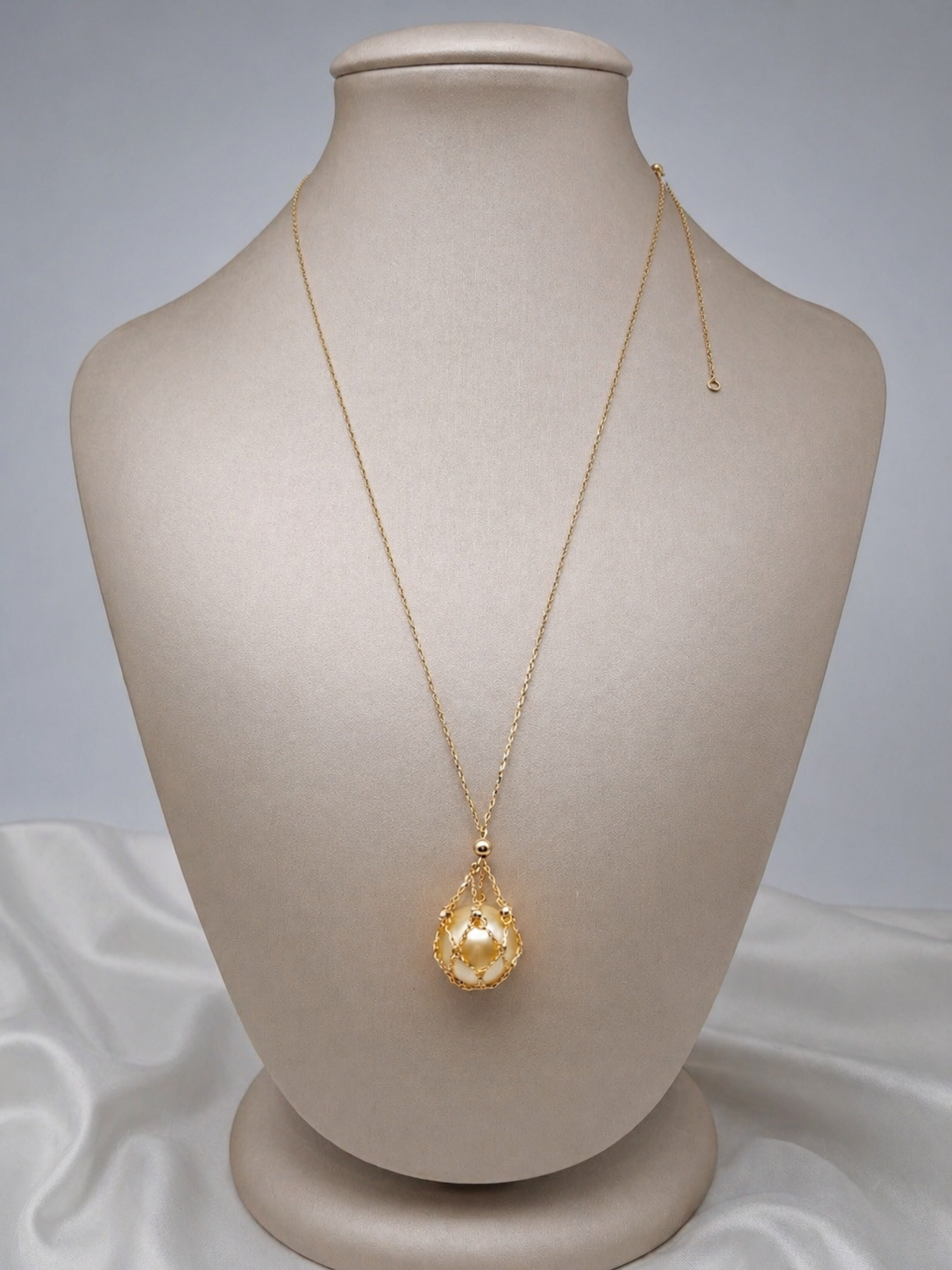 Gold tone pendant necklace with teardrop net charm and golden pearl bead centerpiece