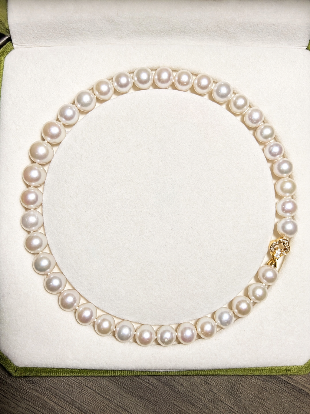 All-pearl bead necklace on jewelry cushion, single strand with gold-tone clasp