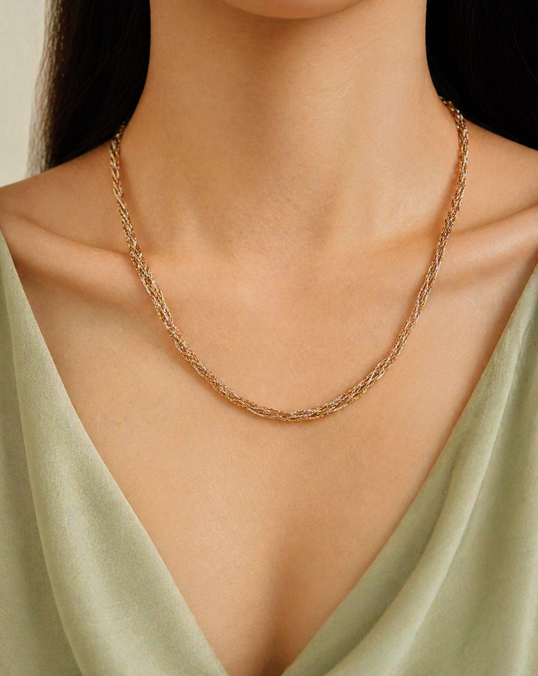 Three-tone gold braided necklace worn at collar on a model, front view