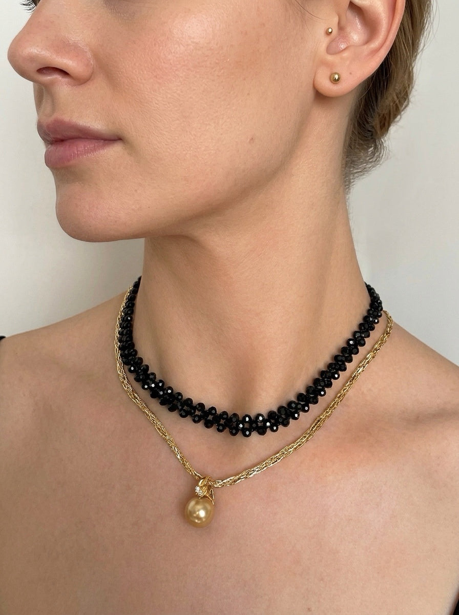 Three-tone gold braided necklace worn by model with gold pendant at center