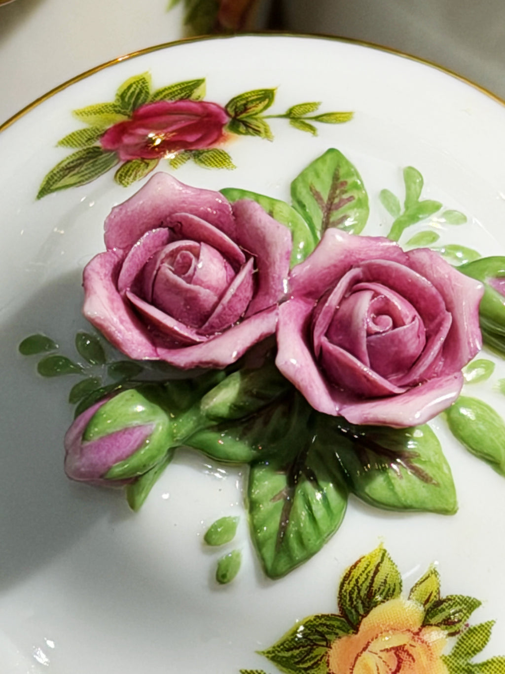 Porcelain jar lid close-up with purple roses and green leaves on white glaze