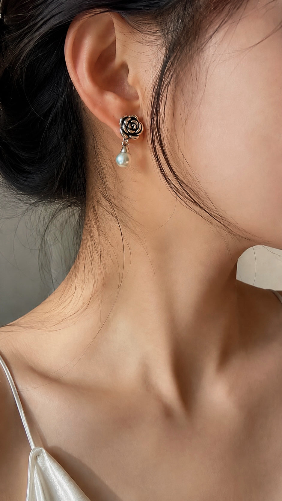 Sterling silver rose drop earrings with gray-blue pearl drop on ear