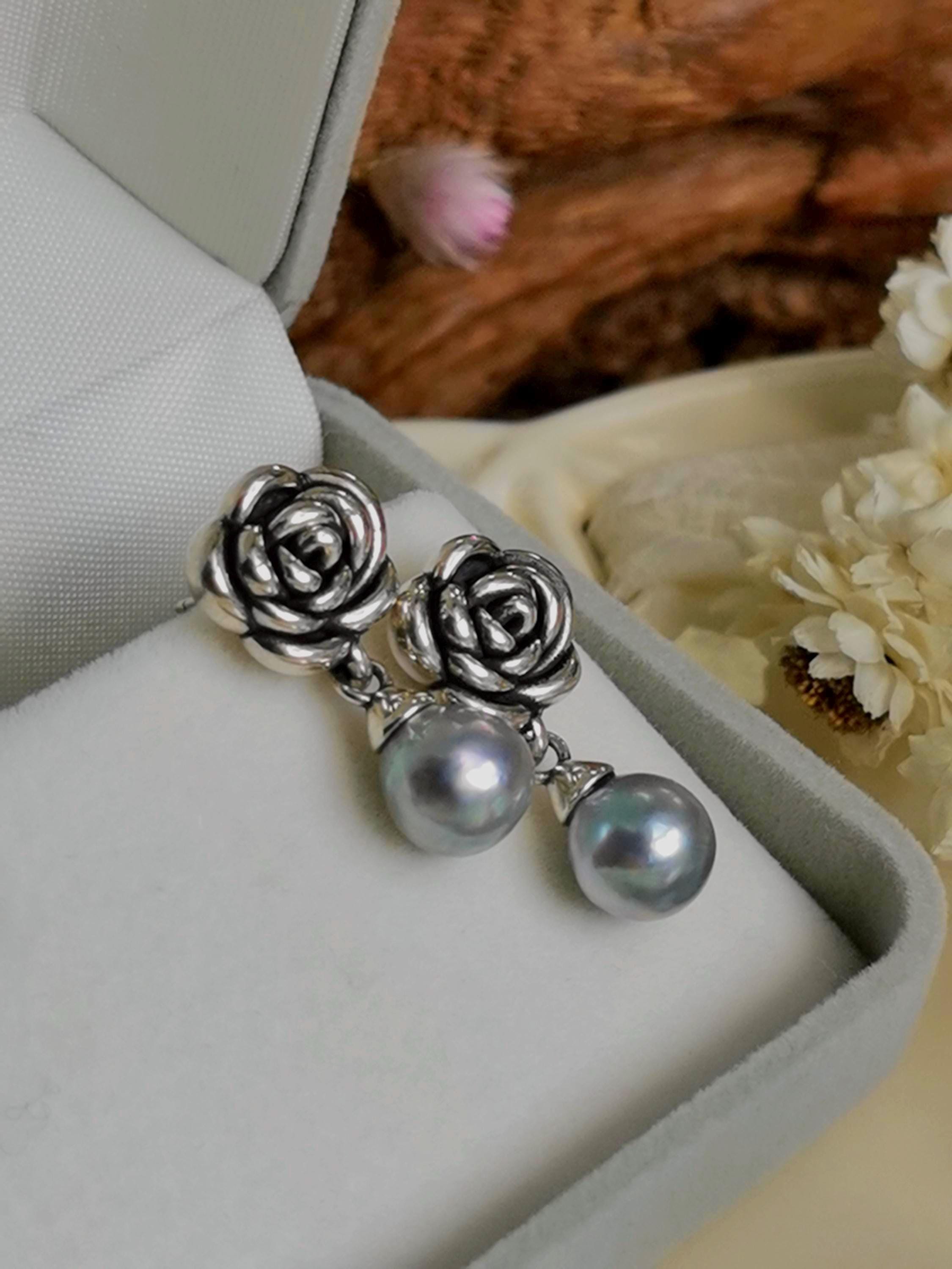 Close-up of silver rose earrings with pearl drops in a jewelry presentation