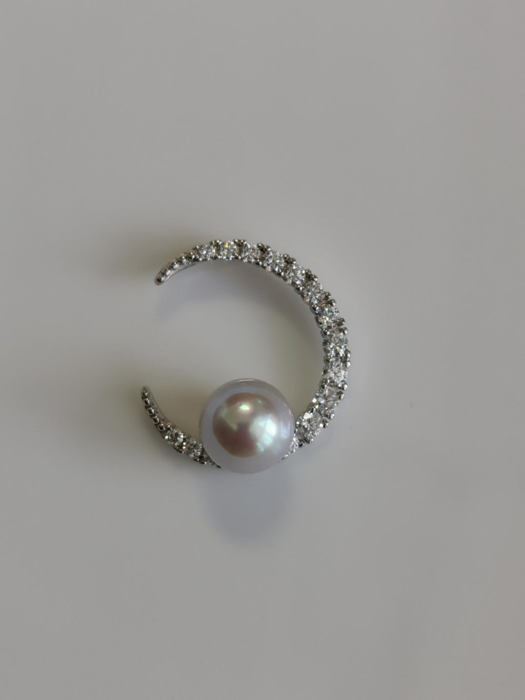 Silver crescent pendant with round pearl and glittering pavé stone surround