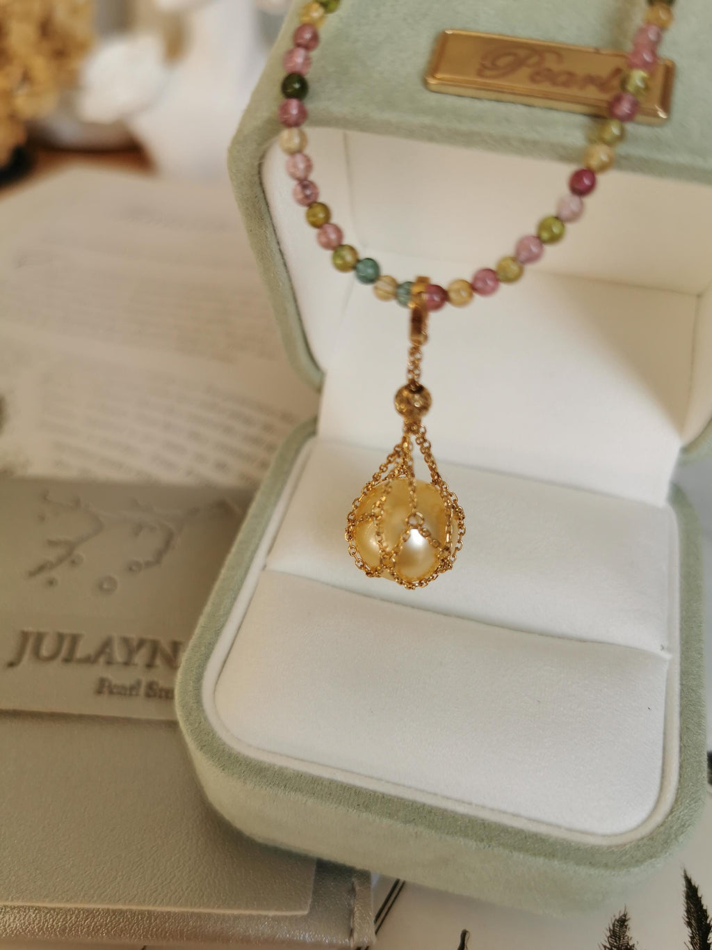 Teardrop pearl net pendant on multicolor bead necklace, shown in box