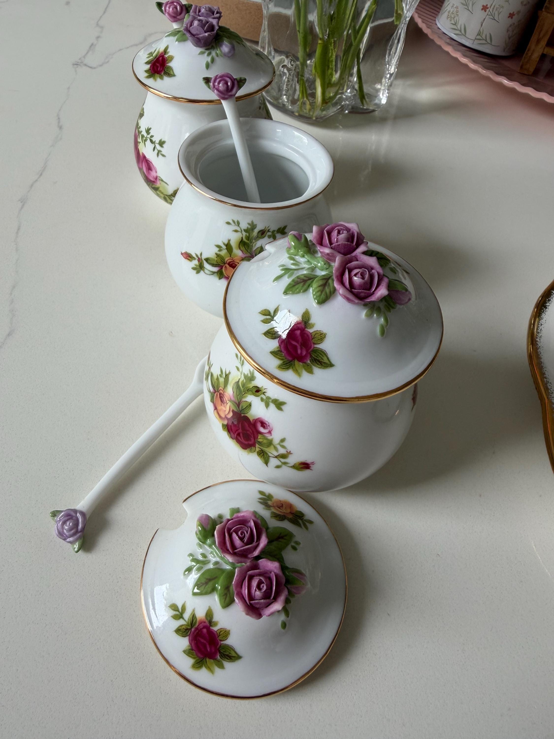 Porcelain sugar jar with spoon and rose floral lid details on white ceramic