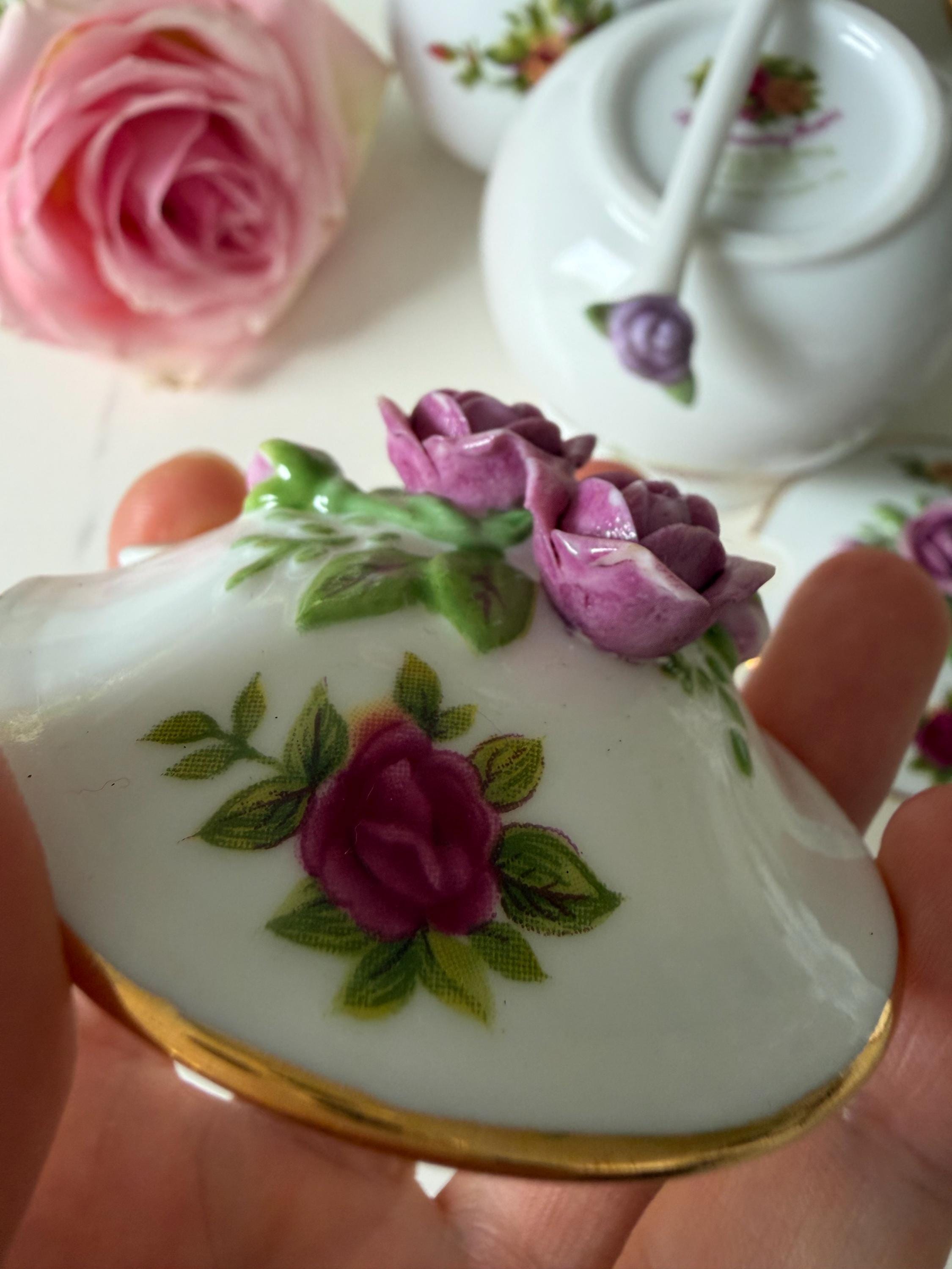 Porcelain jar lid close-up with purple rose motif and green leaves on white glaze